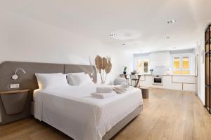 a white bedroom with a large bed and a kitchen at Scalinada Luxury Suites in Corfu Town