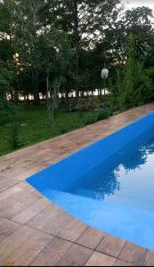 a blue pool in a yard with trees in the background at El Amanecer Don Zenon Lago Urugua-i in Puerto Libertad