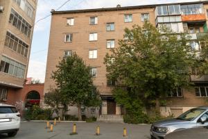 a brick building with cars parked in front of it at Apartment Ural at Svobodi 145A in Chelyabinsk