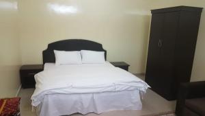 العييري للشقق المفروشة حائل1 في حائل: غرفة نوم مع سرير أبيض وخزانة سوداء