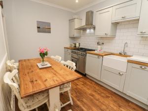 a kitchen with a wooden table and white cabinets at Captains Cottage in Whitby