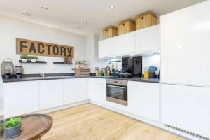 a kitchen with white cabinets and a wooden table at Newly Built Luxury 2 Bed Apartment!!! in London