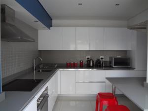 a kitchen with white cabinets and a red stool at Designer Studio Camps Bay in Cape Town