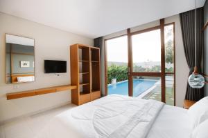 a bedroom with a large bed and a television at Vasudha Hostel Canggu in Canggu +21 photos