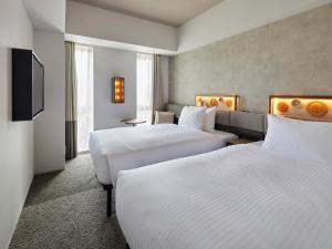 um quarto de hotel com duas camas e uma televisão de ecrã plano em Susukino Granbell Hotel em Sapporo