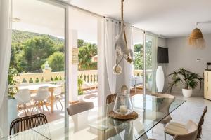 a living room with a glass table in front of a balcony at Villa Felicidad in Font de Sa Cala