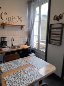 een keuken met een tafel, een wastafel en een raam bij Le Samwest in Arromanches-les-Bains