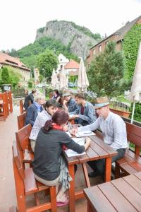 un gruppo di persone seduti su un tavolo di legno di Hotel Obecná Škola a Svatý Jan pod Skalou