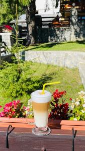 a drink sitting on top of a wooden table at Pensiunea Kalinder in Buşteni