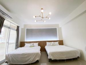 a bedroom with two beds and a chandelier at Kun Inn - Nandao in Taitung City