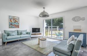 a living room with two couches and a tv at Maison vue mer dans le Golfe du Morbihan in Baden