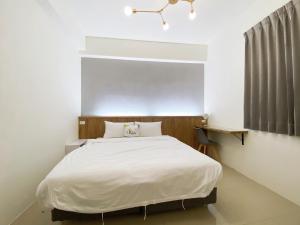 a bedroom with a large white bed in a room at Kun Inn - Nandao in Taitung City