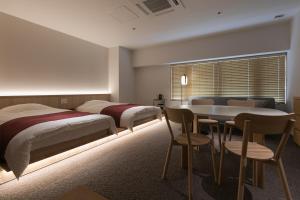 京都的住宿－Design Hotel Kyoto Fuyacho，一间卧室配有两张床和一张桌子及椅子