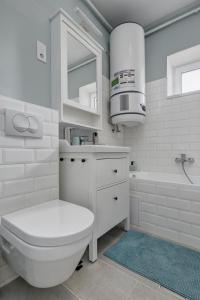 a white bathroom with a toilet and a sink and a tub at Virágos Vendégház a Dunakanyarban, privát kerttel in Nagymaros