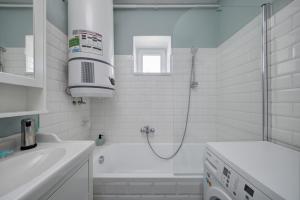 y baño blanco con ducha y bañera. en Virágos Vendégház a Dunakanyarban, privát kerttel, en Nagymaros