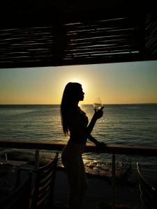 a woman holding a glass of wine in front of the ocean at Side Kleopatra Hotel in Side