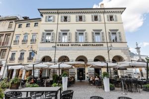 a building with tables and umbrellas in front of it at Oriana Homèl Udine in Udine