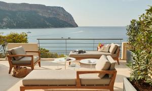 
a dining room table with chairs and a balcony overlooking the ocean at Hôtel Les Roches Blanches Cassis in Cassis

