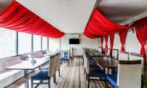 a restaurant with red curtains and tables and chairs at Treebo Trend Concerto Residentia in Durgāpur