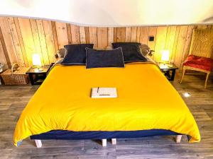 a yellow bed in a room with two tables at Les Volets Rouges in Arbois