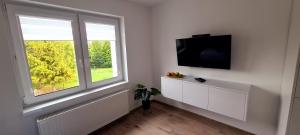 a white room with a tv and a window at Apartamenty Happy in Lębork