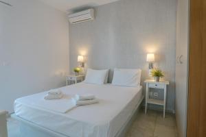 a bedroom with a white bed with towels on it at Indigo Studios in Livadi