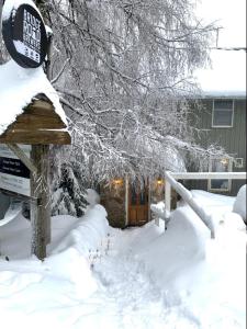 un cartel en la nieve frente a una casa en Feathertop Alpine Lodge, en Falls Creek