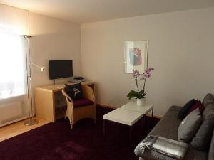 a living room with a couch and a desk with a television at Ferienwohnung Brüssing in Pentling