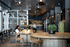 a woman sitting at a bar in a restaurant at Comfort Hotel Børsparken in Oslo