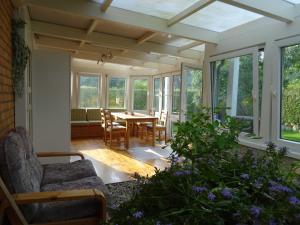 a conservatory with a table and chairs and windows at Kommod Stuv in Langstedt