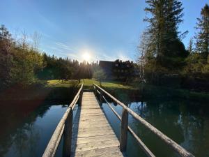 un puente de madera sobre un lago con el sol al fondo en Willa Arnika, en Lutowiska
