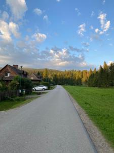 a road with a car parked on the side at Willa Arnika in Lutowiska