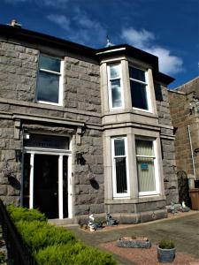 une maison en pierre avec une porte blanche et des fenêtres dans l'établissement Vaila Guest House, à Aberdeen