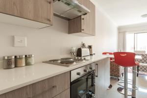 uma cozinha com um fogão e um banco vermelho em The Rand Haven em Midrand