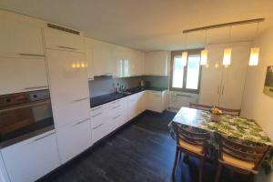 a kitchen with white cabinets and a table with chairs at Schöne 3 1/2 Zimmer Wohnung in der Zentralschweiz in Menznau