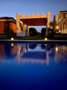 a swimming pool in front of a house at night at Devmani Hotel Rural in Espartinas