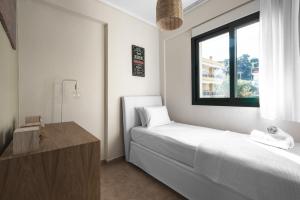 a white bedroom with a bed and a window at Melba's Residence Polihrono by Luxlikehome in Polychrono
