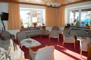 een wachtkamer met stoelen, tafels en ramen bij Hotel Tauernpasshöhe in Obertauern