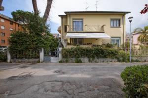 een geel huis met een veranda en een hek bij Il Pino Marittimo in Viareggio