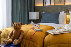 - un ours en peluche assis sur un lit dans une chambre d'hôtel dans l'établissement Hotel Dadou Paris, à Paris