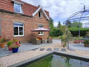 a brick house with a swimming pool and a patio at PAVILLON DU GARDE CHASSE in Bugnicourt