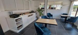 cocina con mesa, sillas azules, mesa y barra en Hotel La Cascada, en Bredene