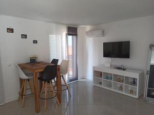 a living room with a table and chairs and a television at Apartman Stella Rovanjska in Rovanjska