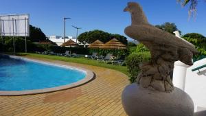 a statue of a chicken standing next to a swimming pool at Debimar Apartamentos in Albufeira