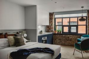 a bedroom with a bed and a kitchen with a window at Leven Manchester in Manchester