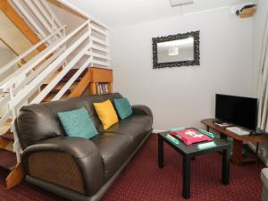 a living room with a leather couch and a television at Turtle Chalet in Dawlish