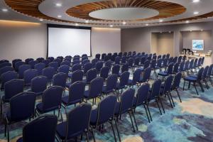 een conferentiezaal met blauwe stoelen en een projectiescherm bij Hyatt Place Aruba Airport in Oranjestad