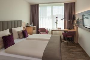 a hotel room with two beds and a television at Essential by Dorint Basel City in Basel