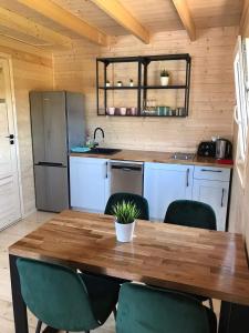 a kitchen with a wooden table and green chairs at Krysiakowe Chatki in Gąski