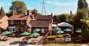 un bâtiment avec des tables et des parasols verts devant lui dans l'établissement SPITTAL BROOK, à Stafford